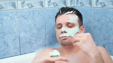 Young man is removing alginate mask from his face lying in bathroom with foam. Stock-Footage 158844802