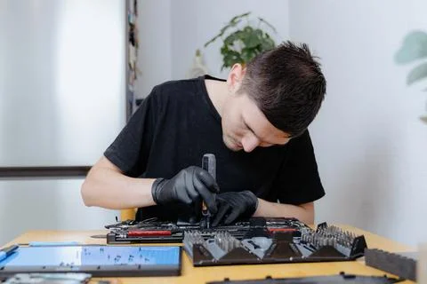 A young man repairs a computer at home. 库存照片