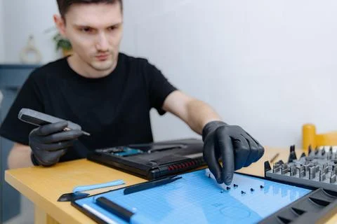 A young man repairs a computer at home. 库存照片