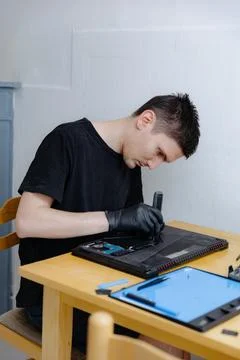 A young man repairs a computer at home. 库存照片