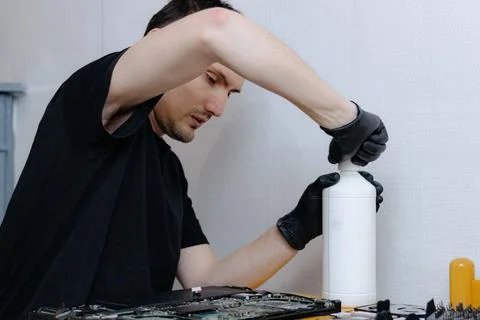 A young man repairs a computer at home. Stock Photos