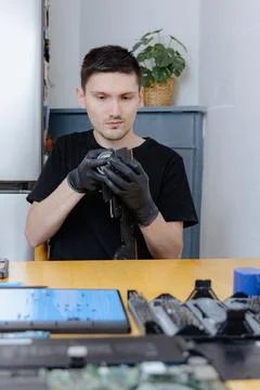 A young man repairs a computer at home. Stock Photos