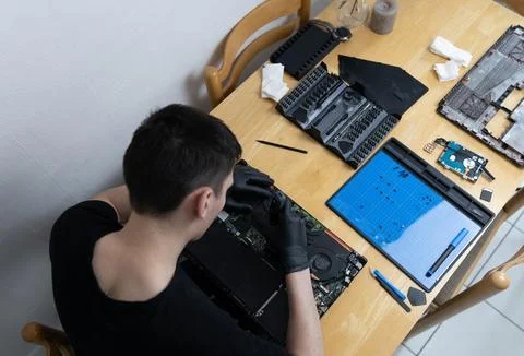 A young man repairs a computer at home. Stock Photos