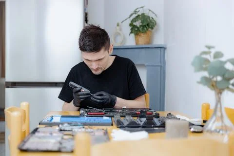 A young man repairs a computer at home. Stock Photos