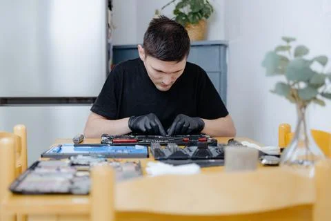 A young man repairs a computer at home. 库存照片