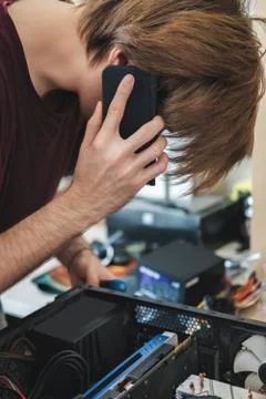 Young man repairs a computer system unit, changes parts, video card and hard Stock Photos
