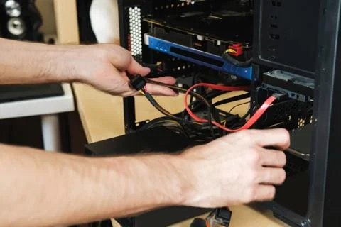 Young man repairs a computer system unit, changes parts, video card and hard Stock Photos