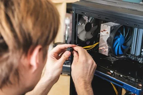 Young man repairs a computer system unit, changes parts, video card and hard Stock Photos