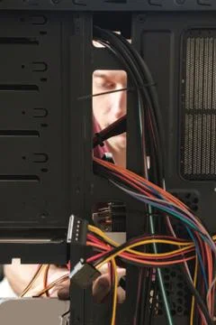 Young man repairs a computer system unit, changes parts, video card and hard Stock Photos