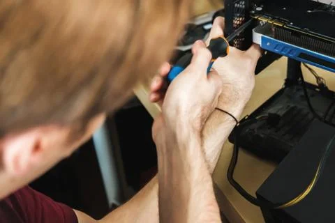 Young man repairs a computer system unit, changes parts, video card and hard Stock Photos