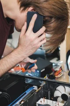 Young man repairs a computer system unit, changes parts, video card and hard Stock Photos