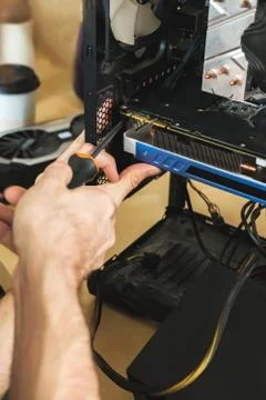 Young man repairs a computer system unit, changes parts, video card and hard Stock Photos