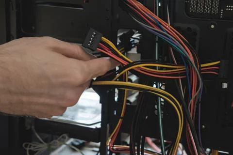 Young man repairs a computer system unit, changes parts, video card and hard Stock Photos
