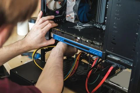 Young man repairs a computer system unit, changes parts, video card and hard Stock Photos