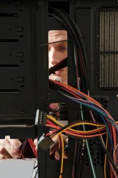 Young man repairs a computer system unit, changes parts, video card and hard Stock-Fotos