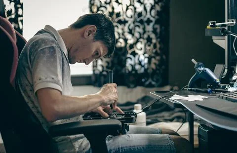 A young man repairs the engine steering wheel on a joystick. Stock Photos