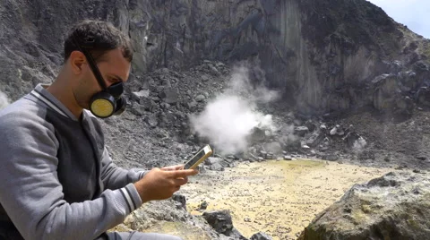 Young man in respirator mask using tablet at Sibayak volcano, North Sumatra Stock Footage 67200952