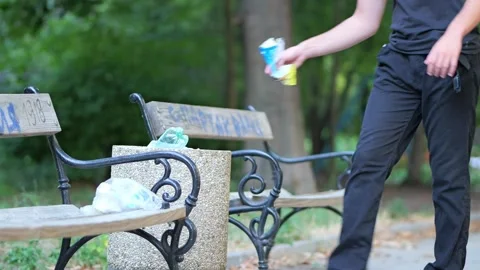 Young man responsibly throwing garbage into a park trash can Stock Footage 340921475