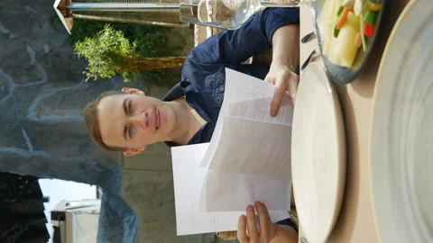 Young man in a restaurant reading and discussing a script .vertical video Stockbeeldmateriaal 136776778