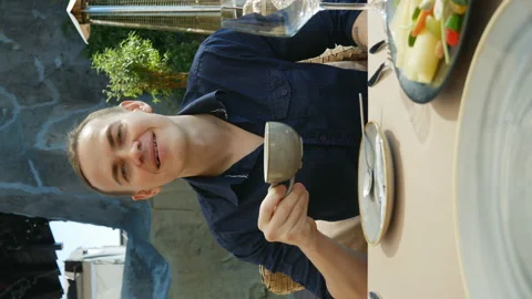 A young man in a restaurant, talks and drinks coffee. vertical video Stock Footage 137617978