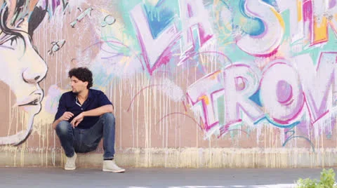 Young man resting after a long walk - beautiful graffiti wall Video stock 26707578