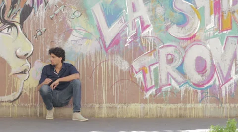 Young man resting after a long walk - beautiful graffiti in background Stock-Footage 28210493
