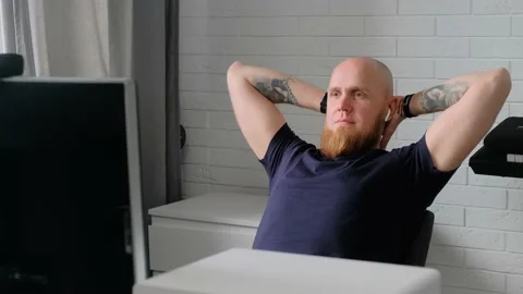 A young man is resting after work, leaning back in a chair. Flex your neck. Stock Footage 139648983