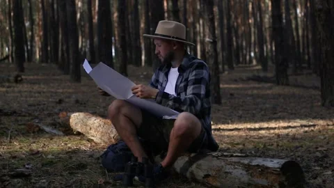 Young man resting and checking the map while hiking in the mountains or forest Stock Footage 150255934