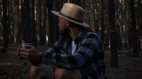 Young man resting and drinking hot tea while hiking in the mountains or forest Stock Footage 150256128