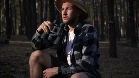 Young man resting and looking through binoculars while hiking Stock Footage 150255983