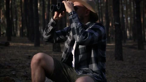 Young man resting and looking through binoculars while hiking Stock Footage 150256008