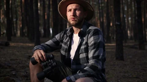 Young man resting and looking through binoculars while hiking Stock Footage 150256032