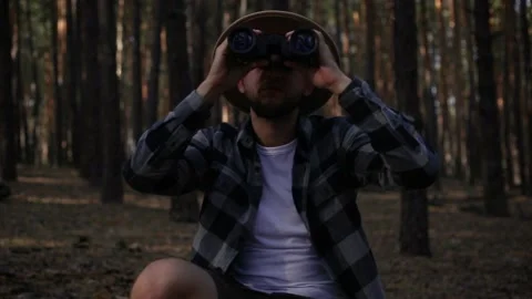 Young man resting and looking through binoculars while hiking in the mountains Video stock 150256153