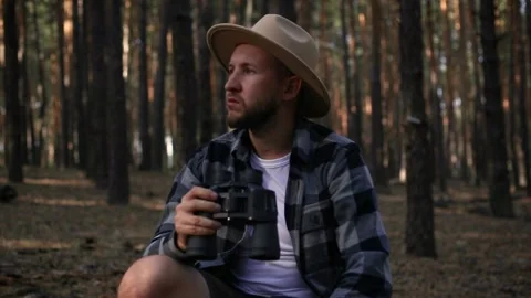 Young man resting and looking through binoculars while hiking in the mountains Video stock 150256260