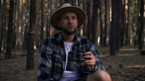 Young man resting and looking through binoculars while hiking in the mountains Stock Footage 150256299