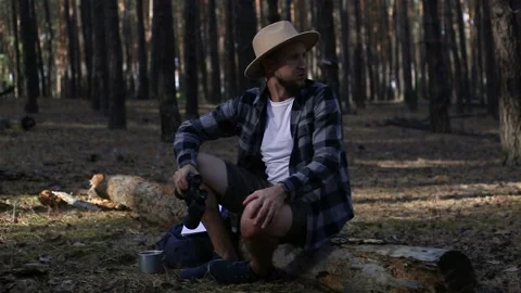 Young man resting on a log and looking through binoculars while hiking Stock Footage 150255729