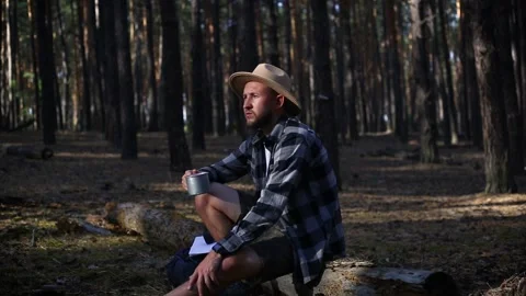 Young man resting on a log while hiking in the mountains or forest at sunset. Stock Footage 150255473