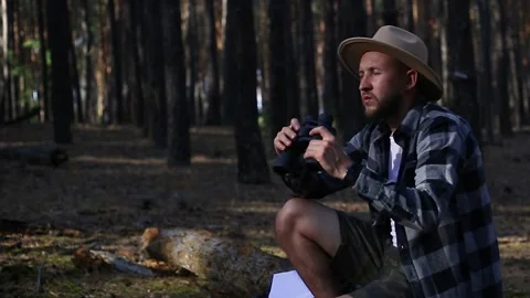 Young man resting on a log while hiking in the mountains or forest at sunset. Stock Footage 150255567