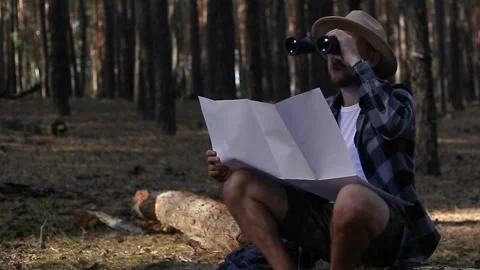 Young man resting, looking through binoculars and checking a map while hiking Stock Footage 150255867