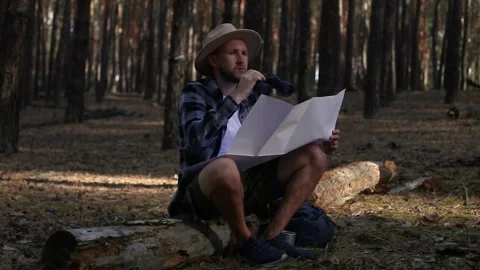 Young man resting, looking through binoculars and checking a map while hiking Stock Footage 150255906