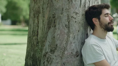 Young man resting pacefully sitting in the park. Close up. Dolly shot Видео 64756749