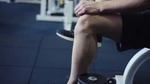 Young man resting while sitting with his feet on a dumbbells Stock Footage 105870777