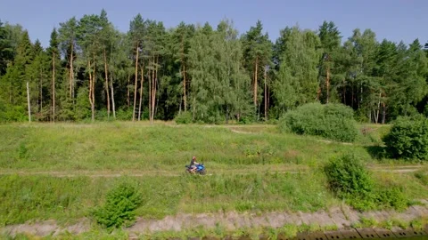 A young man rides a motorcycle outside the city. Drone Stock Footage