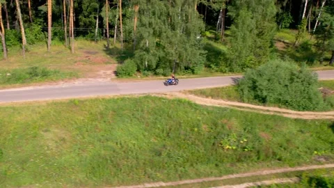 A young man rides a motorcycle outside the city. Drone Stock Footage 169610201