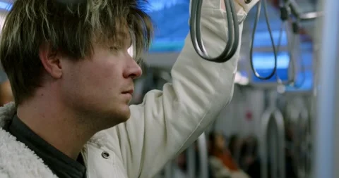 A young man rides in a subway car. A sad tired man rides the subway home from Stock Footage 237400540