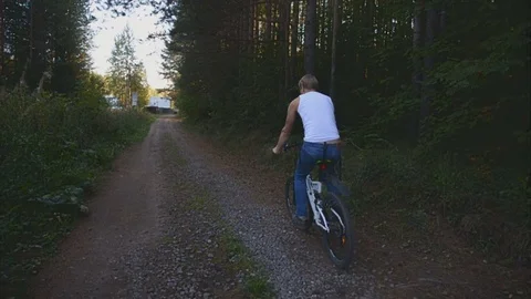 Young man riding a bicycle in the forest Stock Footage 76616693