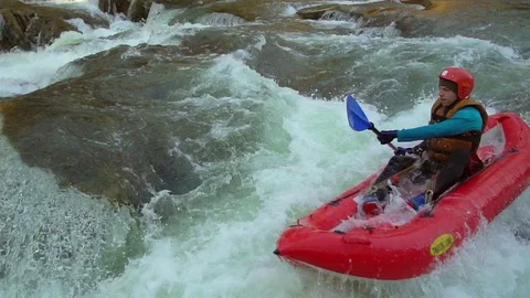 Young man riding on rough mountain river on his inflatable boat, passing stones Video stock 86440388