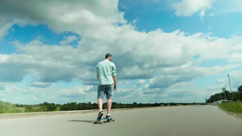 Young man riding a skateboard on empty road. Outdoor workout. Self distancing Stock Footage 134064080