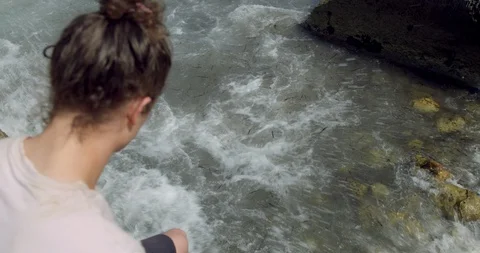 Young Man on a Rock watching Waves in Rocky Cliff. Long Bun Hair Hipster  Stock Footage 94429007