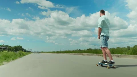 Young man rolling on a long-board alone on a road Outdoors workout Self distance Stock Footage 134063787